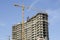 Yellow high-rise crane and house under construction against the blue sky