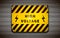 Yellow high voltage sign on metallic grid, industrial background