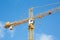 Yellow hoisting crane on blue sky background with clouds