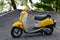 Yellow Honda metropolitan scooter parked on gravel