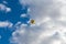 A yellow hot air balloon floats high in the air,
