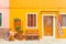 Yellow house with flowers, bench and a bicycle. Colorful houses in Burano island near Venice, Italy. Venice postcard. Famous place