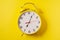 Yellow illuminating color Retro style alarm clock on yellow background