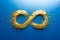 Yellow infinity symbol sign consists of golden confetti against glowing blue background