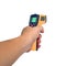 Yellow Infrared thermometer gun in hand used to measure temperature on white