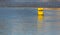 Yellow iron buoy floats in the blue water the river shows the level of the ships