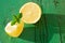 Yellow juicy lemon slices with mint leaves  on wooden green background with hard light, on strong sunlight with long dark shadow,