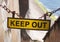 Yellow keep out sign hung on a chain blocking the entrance to concrete sea wall leading to the beach at high tide