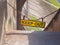 Yellow keep out sign hung on a chain blocking the entrance to concrete sea wall leading to the beach at high tide