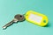 Yellow key tag on a turquoise textured cardboard background.The