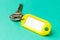 Yellow key tag on a turquoise textured cardboard background.The