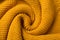 Yellow knitted fabric twisted like a snail shell textured background