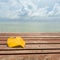 Yellow leaf in form of heart on wood table and autumn cloudy sky sea beach background.
