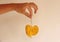 Yellow leaf of a tree in the shape of a heart. A hand holds a sheet