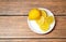 Yellow lemon with lemon slices on a white ceramic plate top view