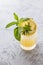 Yellow lemon shrub drink in a rocks glass garnished with herbs