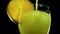 Yellow lemonade on a black background, pour orange juice with ice close-up