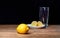 Yellow lemons with lemon pieces on a ceramic plate and a glass behind