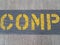 Yellow letter spelling comp on grey cement