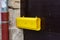 yellow letterbox on dark wooden door