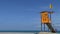 Yellow life guard station with yellow flag at beach.