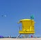 Yellow Life Guard Tower at the beach with people, kite surfer and blue sky