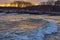 The yellow light of sunset reflects on waves at a beach in New Castle  NH