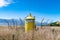 Yellow lighthouse beacon in an overgrown field with mountains and the ocean in the background