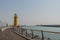 Yellow lighthouse on end of pier on hazy afternoon