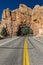 Yellow line divides Utah state highway and drives through Red Rock with hole in center