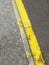 Yellow line in poor condition on asphalt road texture background. Damaged Asphalt road texture with yellow line