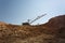 Yellow massive metal mobile crane on a blue sky background. An industrial moving machine in the foundation pit. Copy