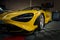Yellow McLaren 765LT showcased in a contemporary tuning garage setting.