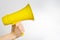 Yellow megaphone in a man`s hand on a white background. Minimalism. Journalism, speaker, advertising, elections, rumors, fakes,