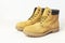 Yellow men`s work boots from natural nubuck leather on wooden white background. Trendy casual shoes, youth style. Concept of