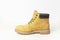 Yellow men`s work boots from natural nubuck leather on wooden white background. Trendy casual shoes, youth style. Concept of