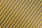 Yellow mesh structure in close-up with backlight on shine morning shows abstract pattern of seamless material textured in golden