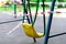 Yellow metal children`s swing on a sports playground in the park