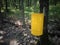 yellow metal garbage bin place outdoor near tree and garden fence