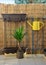 Yellow metal watering can hang on balcony railing, bamboo fence in background