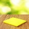 Yellow micro fiber napkins on wooden table against blurred green background. Household