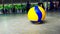 Yellow mingle with blue strips volleyball which is made from synthetic leather on gray concrete floor