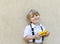 Yellow model of a toy school bus in the hands of a cheerful cute schoolboy in a white shirt