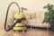 Yellow modern vacuum cleaner in living room. Copy space. Flat clean vacuuming concept. Green monstera plant