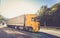 Yellow moving DAF truck coupled with semi-trailer in motion located on the road