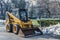 Yellow municipality excavator doing spring cleaning in central park