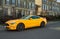 Yellow muscle car Ford Mustang at the countryside. Front headlights of yellow modern car on a street