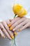 Yellow nail design. Female hand holding yellow tulip