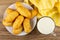 Yellow napkin, cookies in white plate, milk in transparent cup on wooden table. Top view