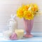Yellow narcissus in vase, candles and decorative heart on blue
